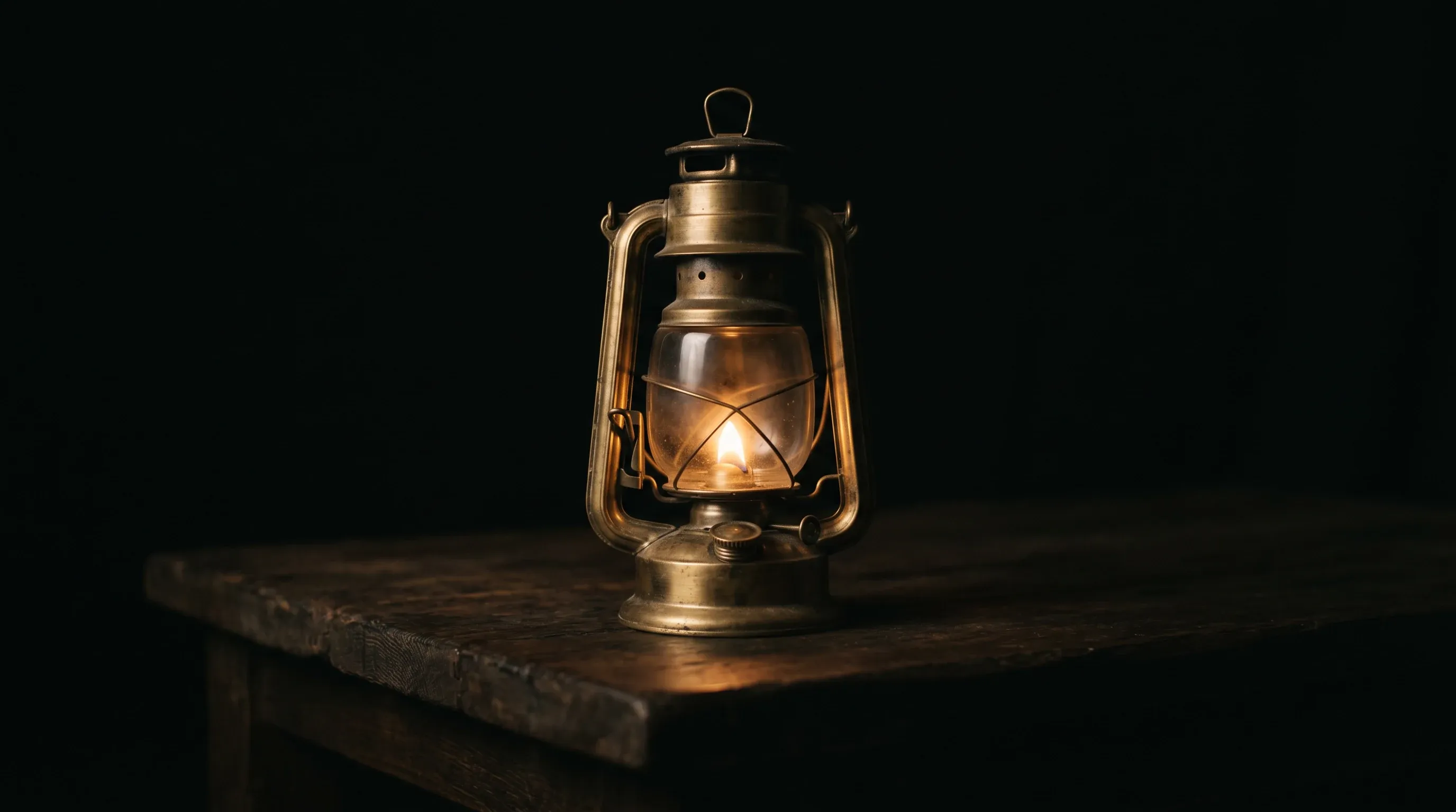 A brass lantern burning on a dark timber table