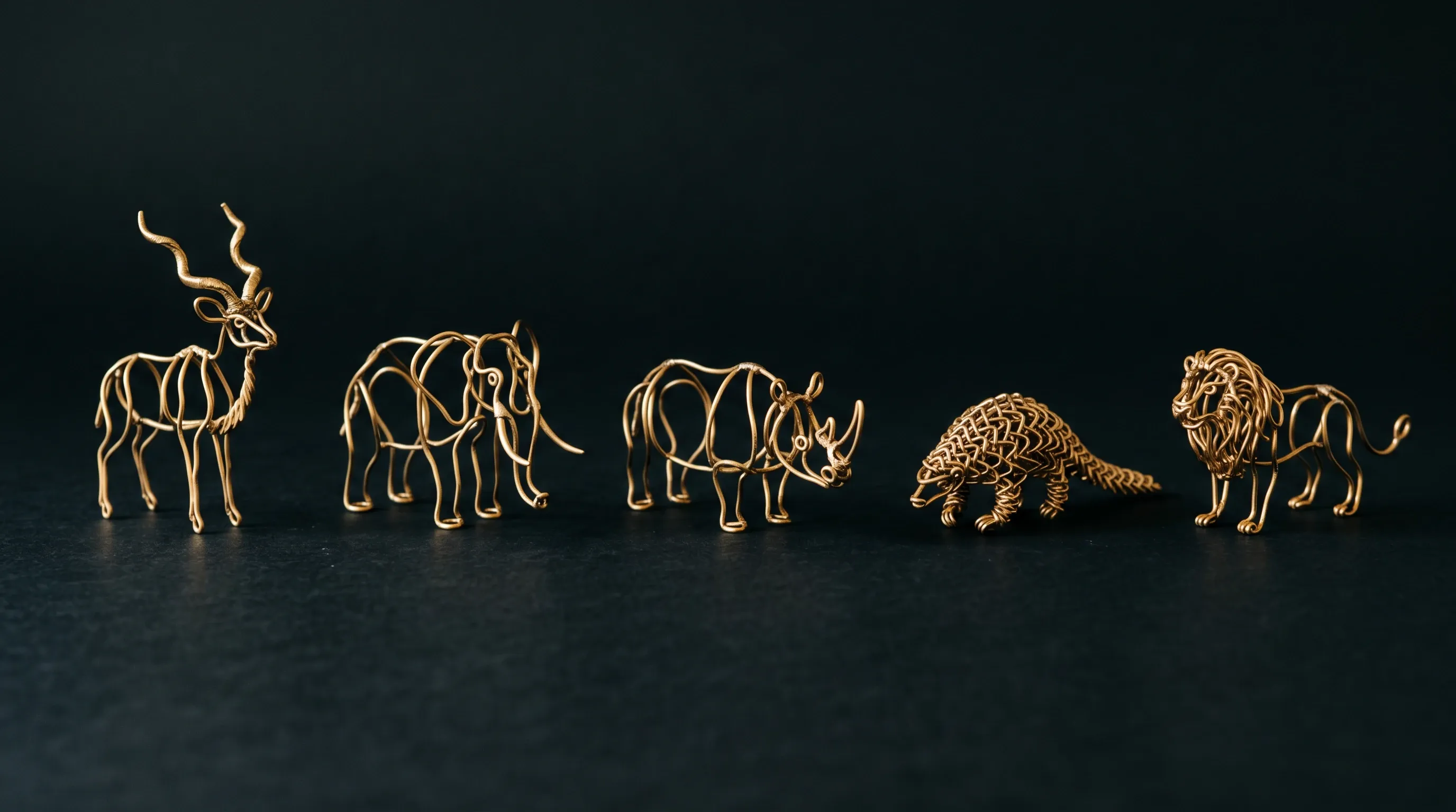 Five brass wire sculptures on a dark ground: kudu, elephant, rhino, pangolin, and lion